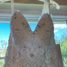 a wedding dress hanging in front of a window