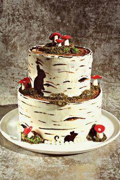 a three tiered cake with white frosting and red mushrooms on top is sitting on a plate