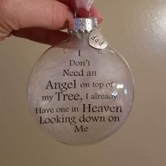 a hand holding a glass ornament that says i don't need an angel on top of my tree, i already have one in heaven looking down on me