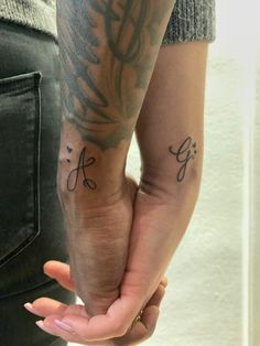 two people holding hands with tattoos on their arms and the word love written in cursive writing