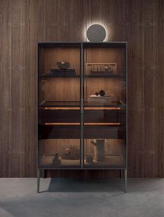 an empty glass cabinet with some items in it and lights on the wall behind it