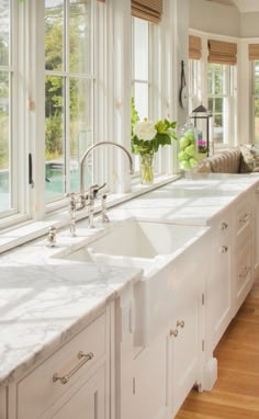 a large kitchen with white cabinets and marble counter tops