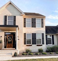 a white house with black shutters on the front door and windows in the side