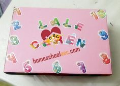 a pink box filled with lots of stickers on top of a white tablecloth