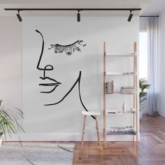 a white wall with a drawing of a face on it and some shelves in front of it