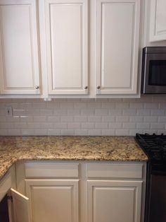 a kitchen with white cabinets and granite counter tops