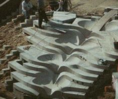 some people are working on an unfinished skate park in the sand with ramps made out of concrete