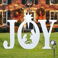 a yard sign that says joy in front of a brick building with wreaths and lights