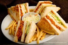 a white plate topped with cut in half sandwiches and french fries