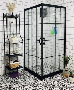 a black and white tiled bathroom with a glass shower enclosure in the corner next to it