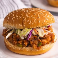 a pulled pork sandwich with coleslaw and slaw on a white bread bun