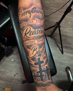 a man's arm with a cross and bible verse tattoo on the left forearm