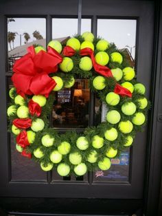 a wreath with tennis balls and red bows on the front door to a storefront