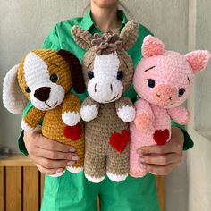 a person holding three stuffed animals in their hands and smiling at the camera while wearing green clothing