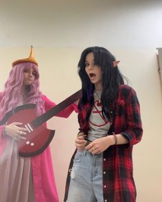 two women dressed in costumes standing next to each other with one holding a guitar and the other wearing a costume