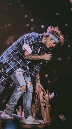 a man standing on top of a stage with lots of hands in front of him