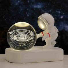 an astronaut touching the inside of a glass ball on a white surface with stars in the background