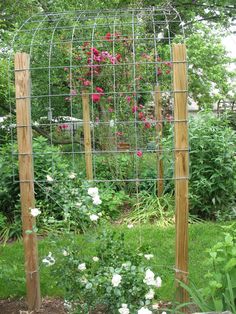 a garden with flowers growing on the side of it and a wire fence around it