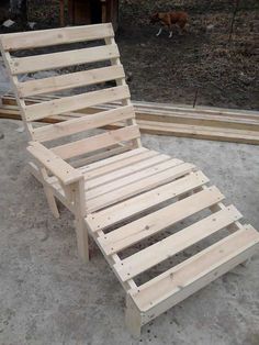 a wooden chaise lounge chair sitting on top of cement ground next to a dog