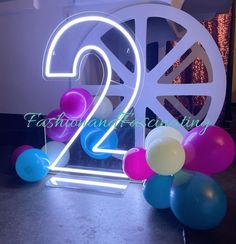 the number twenty two is lit up in front of balloons and a sign that says 2