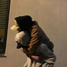 a man carrying a child on his back while walking down the street in front of a building