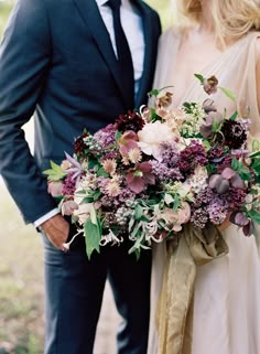 a man and woman standing next to each other with flowers on their wedding bouquets