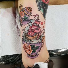 a woman's foot with a ship and roses tattoo design on the left side of her leg