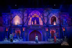 the stage is lit up with purple lighting and people standing on it in front of an ornate building