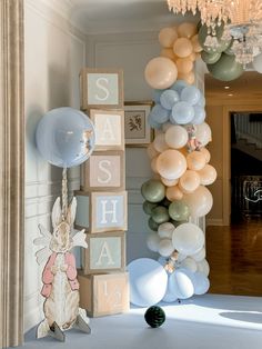 balloons are hanging from the ceiling in front of a wall with letters and animals on it