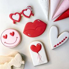 decorated cookies are arranged on a table with red and white icing, including hearts