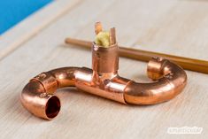 the copper pipe is laying on top of the wooden table next to some pencils