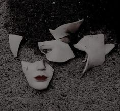 two white masks with red lips are on the ground next to each other and one is broken