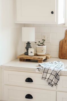 a kitchen counter with white cabinets and black knobs