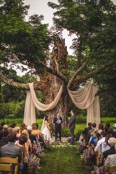 a bride and groom standing at the end of their wedding ceremony under an old tree