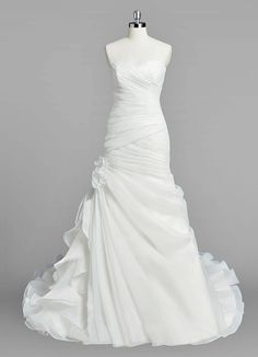 a white wedding dress on a mannequin with ruffles around the skirt