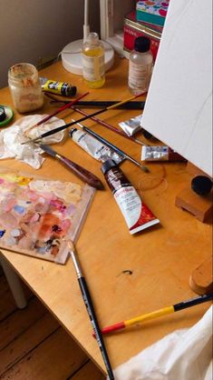 an artist's easel with paint, brushes and other art supplies on it