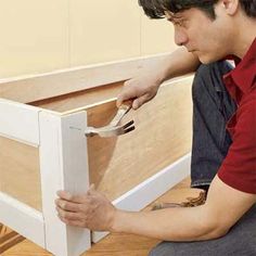 a man is working on the bottom part of a cabinet