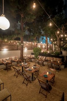 an outdoor seating area with lights strung from the ceiling and tables set up for dinner