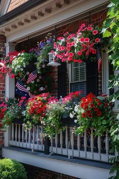 red and white flowers are hanging from the balconies on this house's front porch