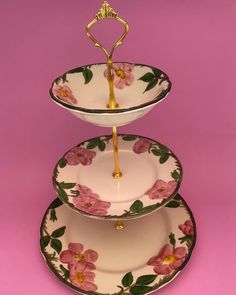 three plates stacked on top of each other with gold handles and pink flowers painted on them