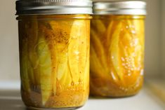 two jars filled with pickles sitting on top of a counter