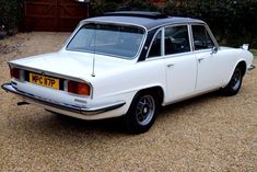 an old white station wagon parked in gravel