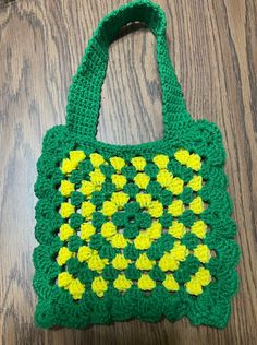 a green crocheted bag sitting on top of a wooden table