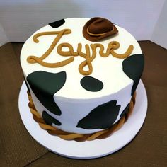 a birthday cake decorated with cow print and the word zayere on top is sitting on a table