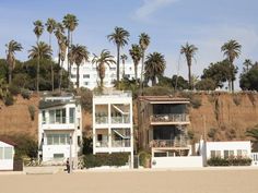 two buildings on the beach with palm trees in the background