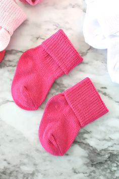 three pairs of pink socks sitting on top of a marble counter