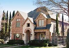 a large brick house with lots of windows and bushes around it's front yard