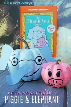 an elephant and piggie pumpkin sitting next to each other in front of a book