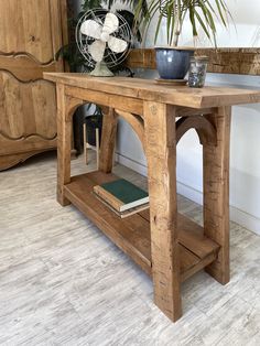 a wooden table with books on it and a fan in the corner next to it