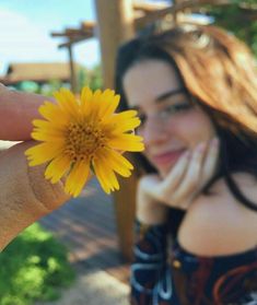 a woman holding a yellow flower in her hand